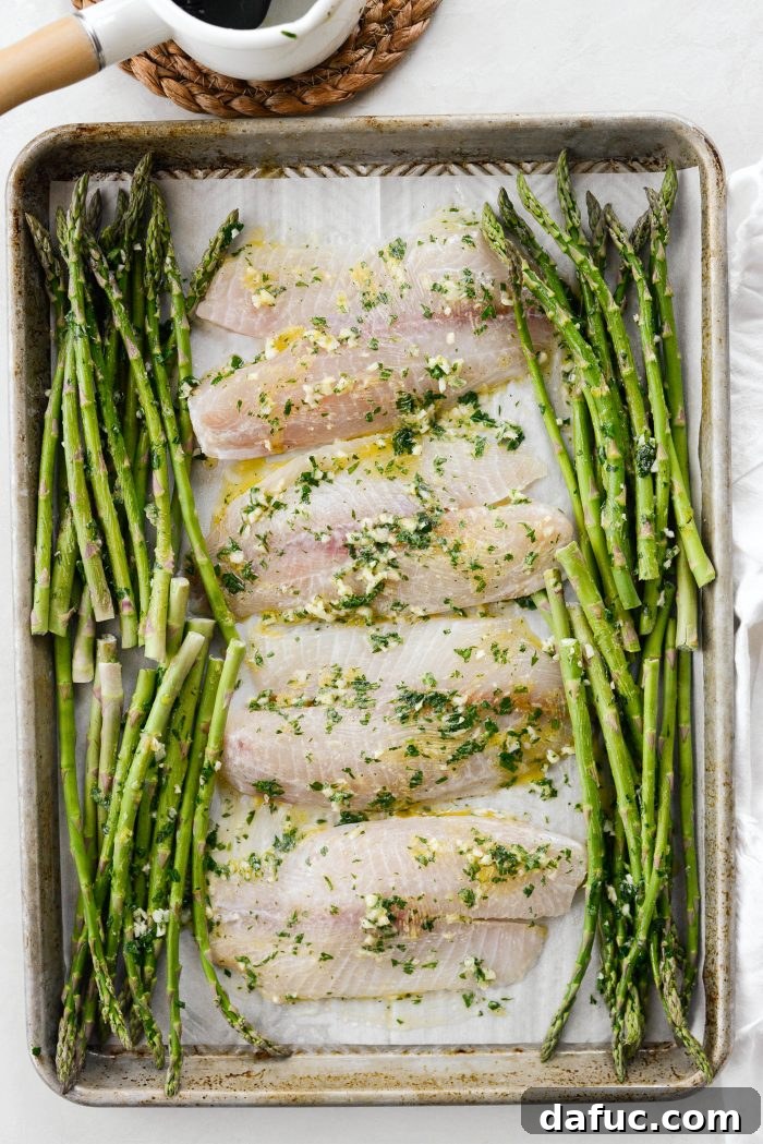 Sheet pan with tilapia and asparagus baking in the oven for 10 minutes