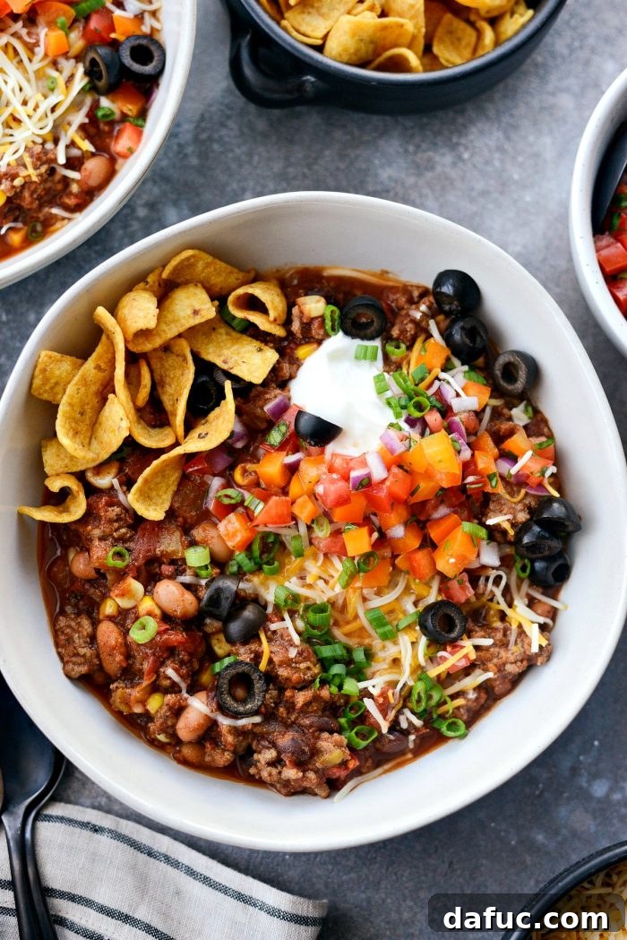 Fiesta Slow Cooker Taco Chili 2 A hearty bowl of Slow Cooker Taco Chili topped with fresh cilantro and a dollop of sour cream, served with tortilla chips on the side. Ideal for a cozy meal or game day.