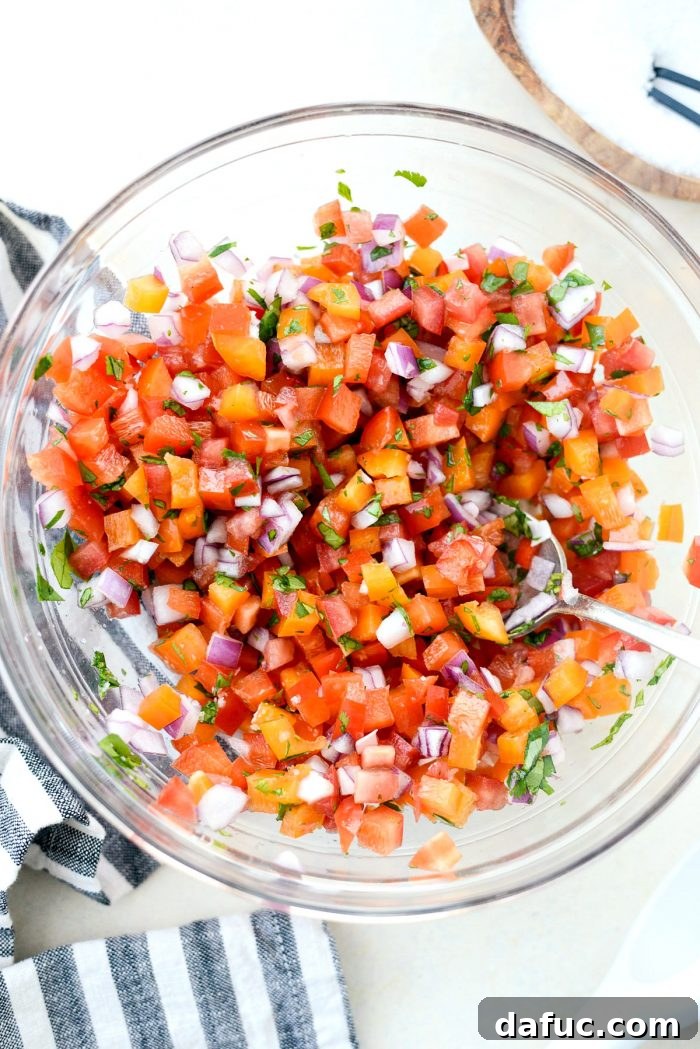 Fiesta Slow Cooker Taco Chili 14 The fresh ingredients for Bell Pepper Pico de Gallo, including tomatoes, bell peppers, red onion, cilantro, salt, and lime juice, stirred together in a bowl.