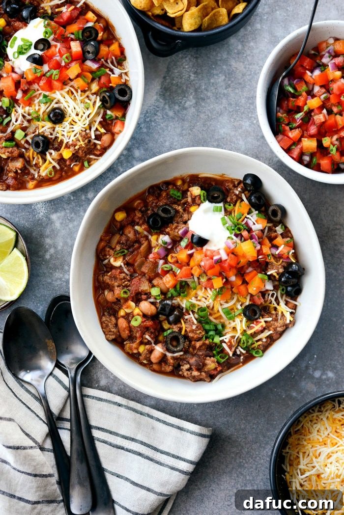 Fiesta Slow Cooker Taco Chili 15 A beautifully garnished bowl of Slow Cooker Taco Chili, featuring Greek yogurt, shredded cheese, homemade pico de gallo, black olives, and green onions.
