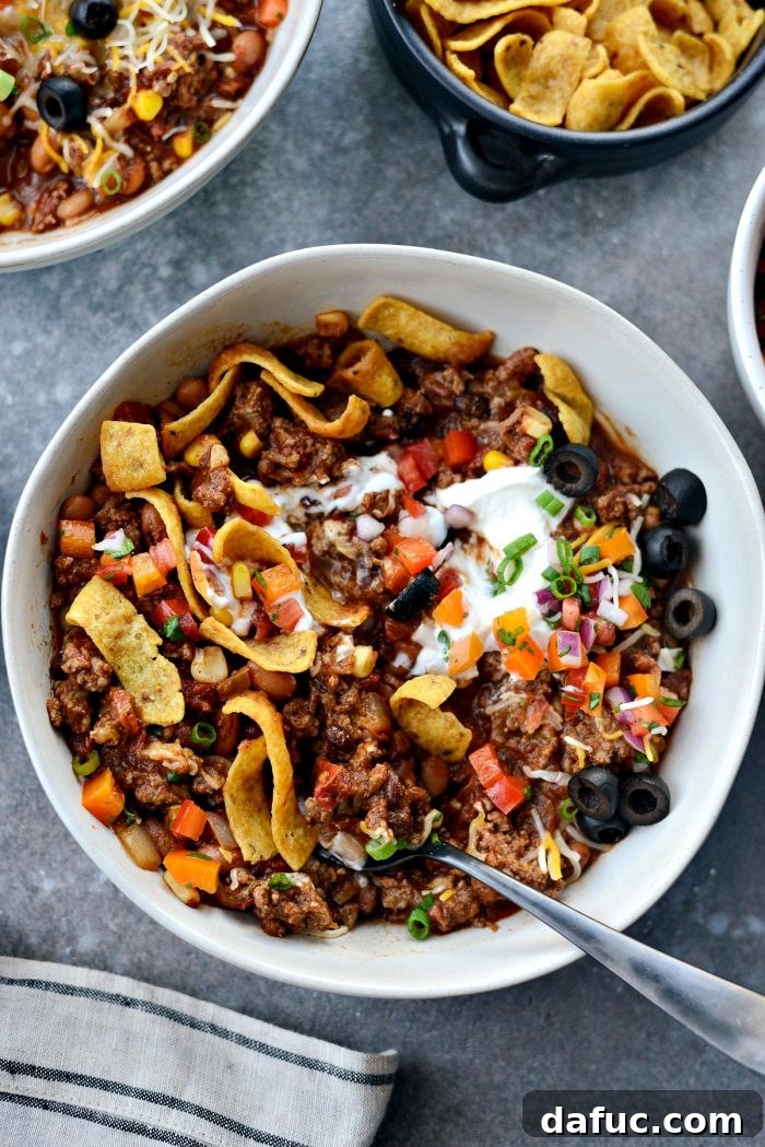 Fiesta Slow Cooker Taco Chili 18 Another enticing shot of Slow Cooker Taco Chili in a bowl with a full spread of toppings and corn chips, showcasing a complete meal.
