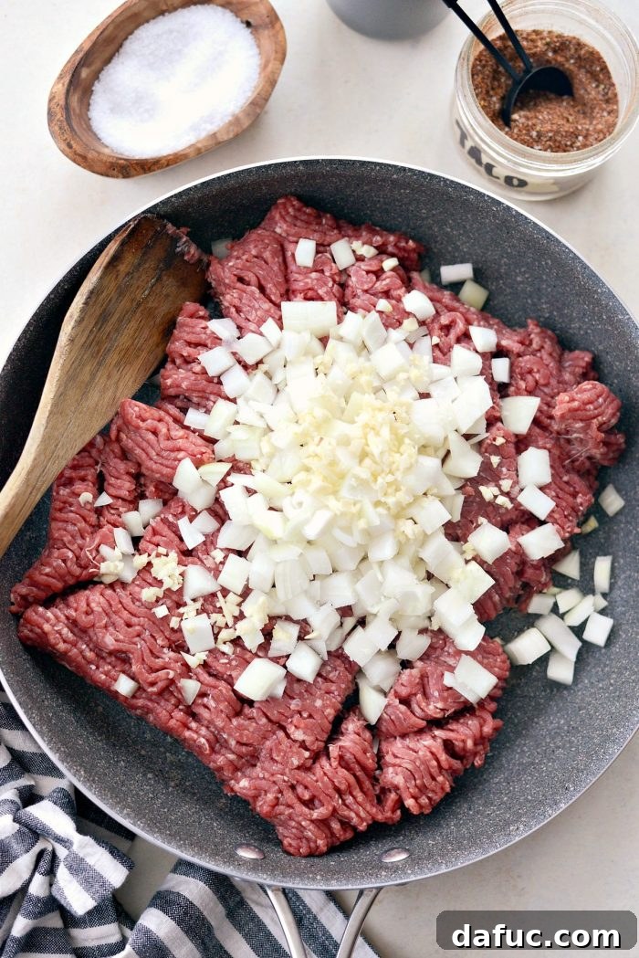 Fiesta Slow Cooker Taco Chili 5 Sautéing lean ground beef, diced yellow onion, and minced garlic in a large skillet, the first step in making Slow Cooker Taco Chili.