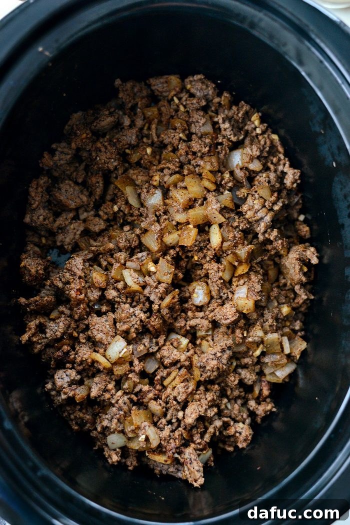 Fiesta Slow Cooker Taco Chili 7 Cooked ground beef, onions, and garlic seasoned with homemade taco seasoning in a skillet, ready to be transferred to the slow cooker.