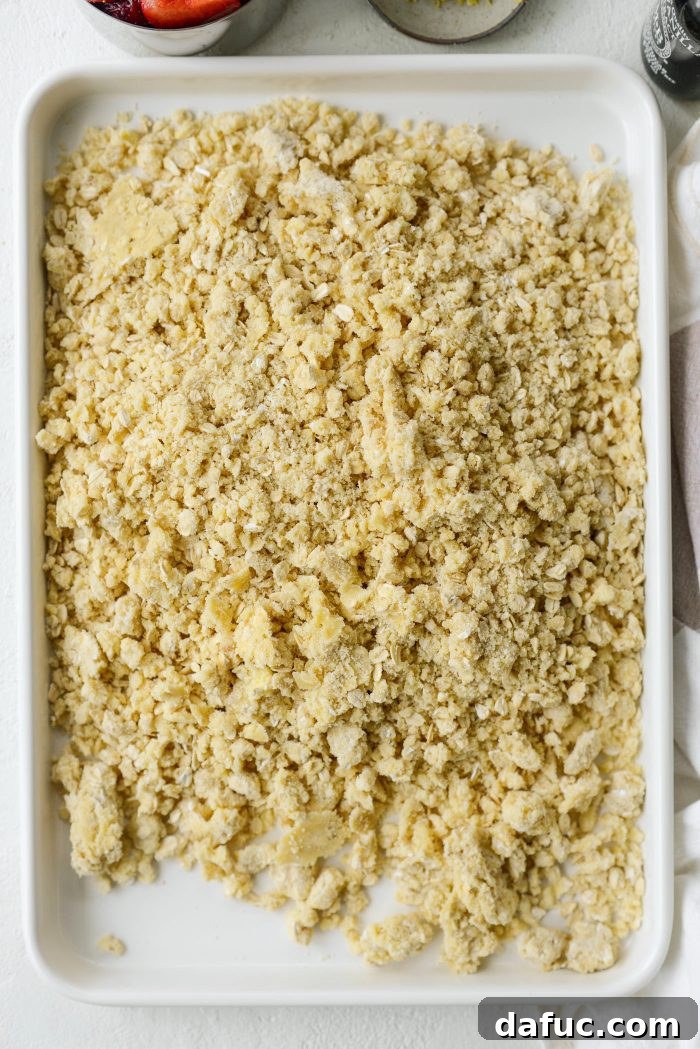 Pressing streusel mixture into a jelly roll pan to form the bar crust