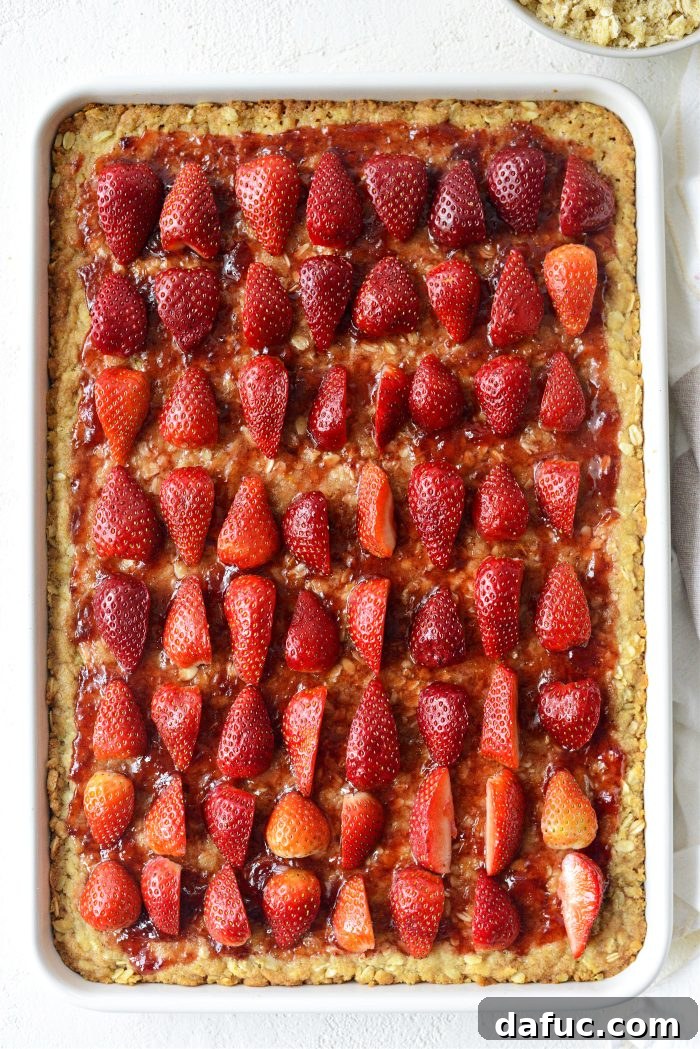 Arranging quartered fresh strawberries evenly over the jam layer