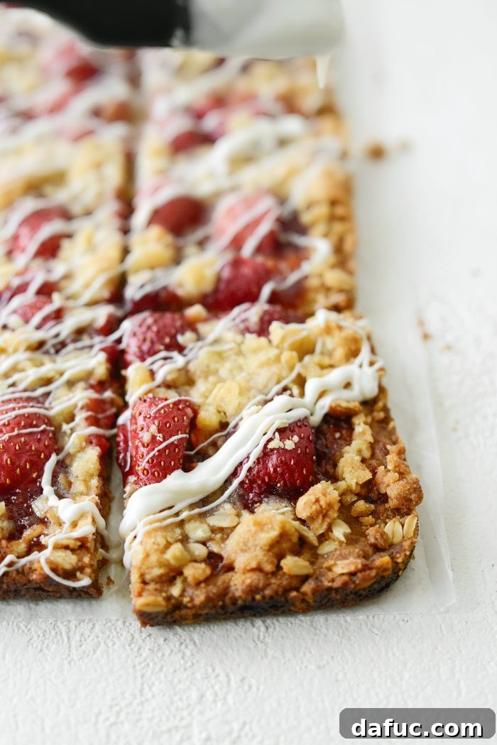Drizzling melted white chocolate over cooled strawberry streusel bars