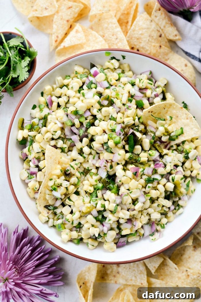 Chipotle's Signature Sweet Corn Salsa 2 Chipotle-style Sweet Corn Salsa in a rustic white bowl, garnished with fresh cilantro, ready to be served. The image showcases the vibrant colors of yellow corn, green peppers, and red onion, making it highly appealing for a copycat recipe.