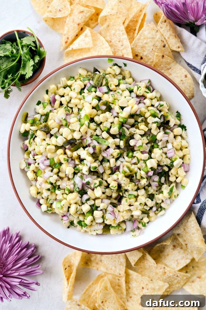 Chipotle's Signature Sweet Corn Salsa 11 A vibrant and fresh bowl of homemade Chipotle Sweet Corn Salsa, garnished with a sprig of cilantro, presented with a serving spoon, inviting viewers to enjoy its rich flavors and textures.