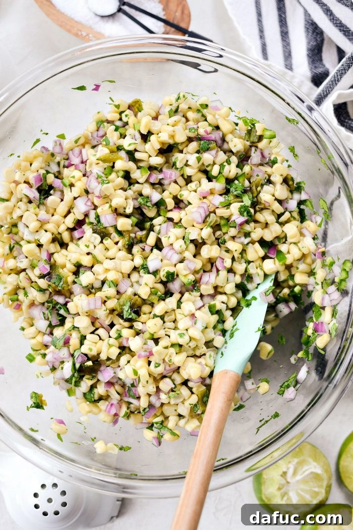 Chipotle's Signature Sweet Corn Salsa 10 The finished sweet corn salsa mixture in a glass bowl, after all ingredients have been thoroughly combined and seasoned with lime juice, sugar, and salt. It appears vibrant and ready to be served or chilled.