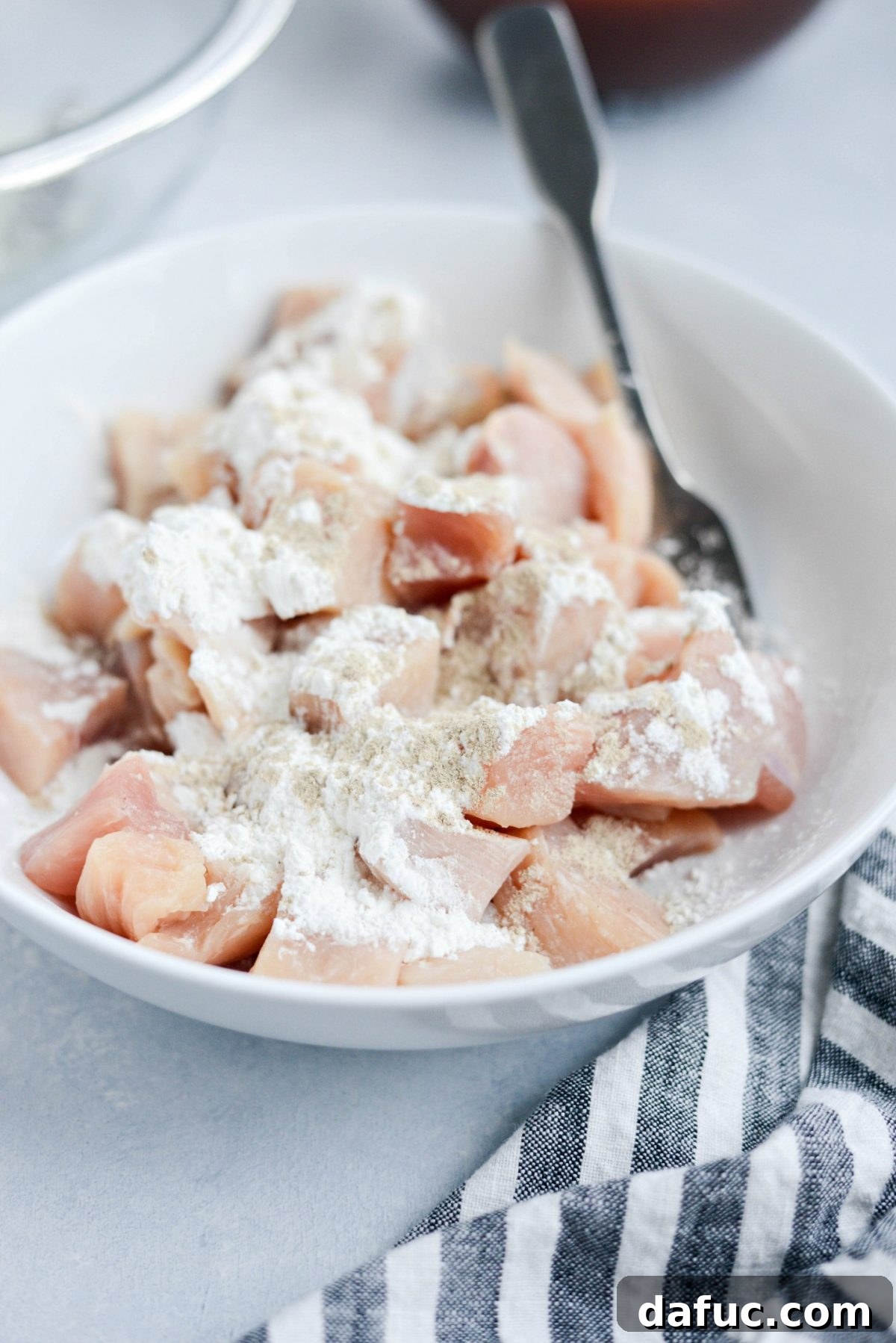 White bowl with chopped chicken, corn starch and ground white pepper.