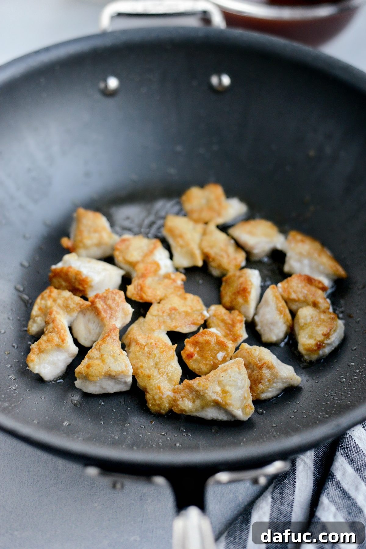 wok with oil and browned chicken