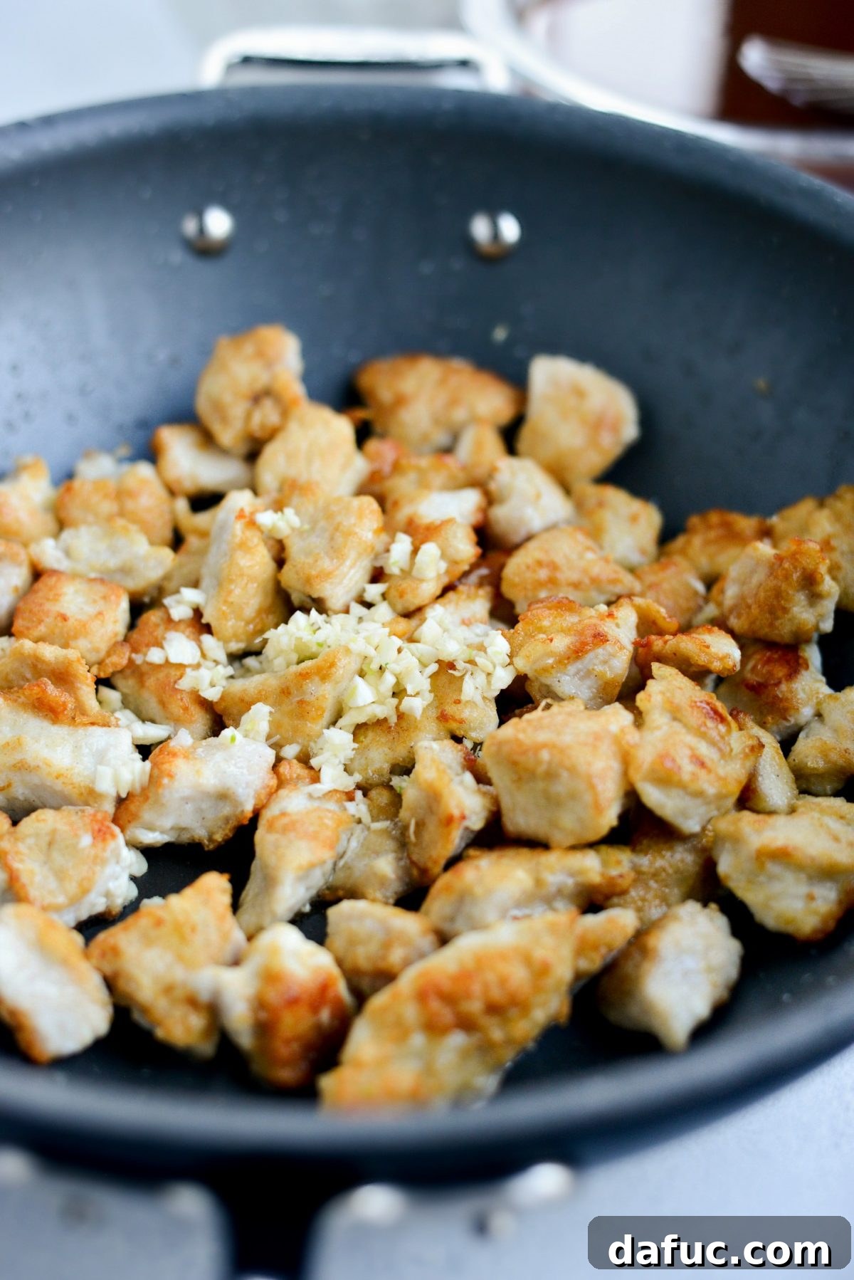 minced garlic added to pan of crispy browned chicken 