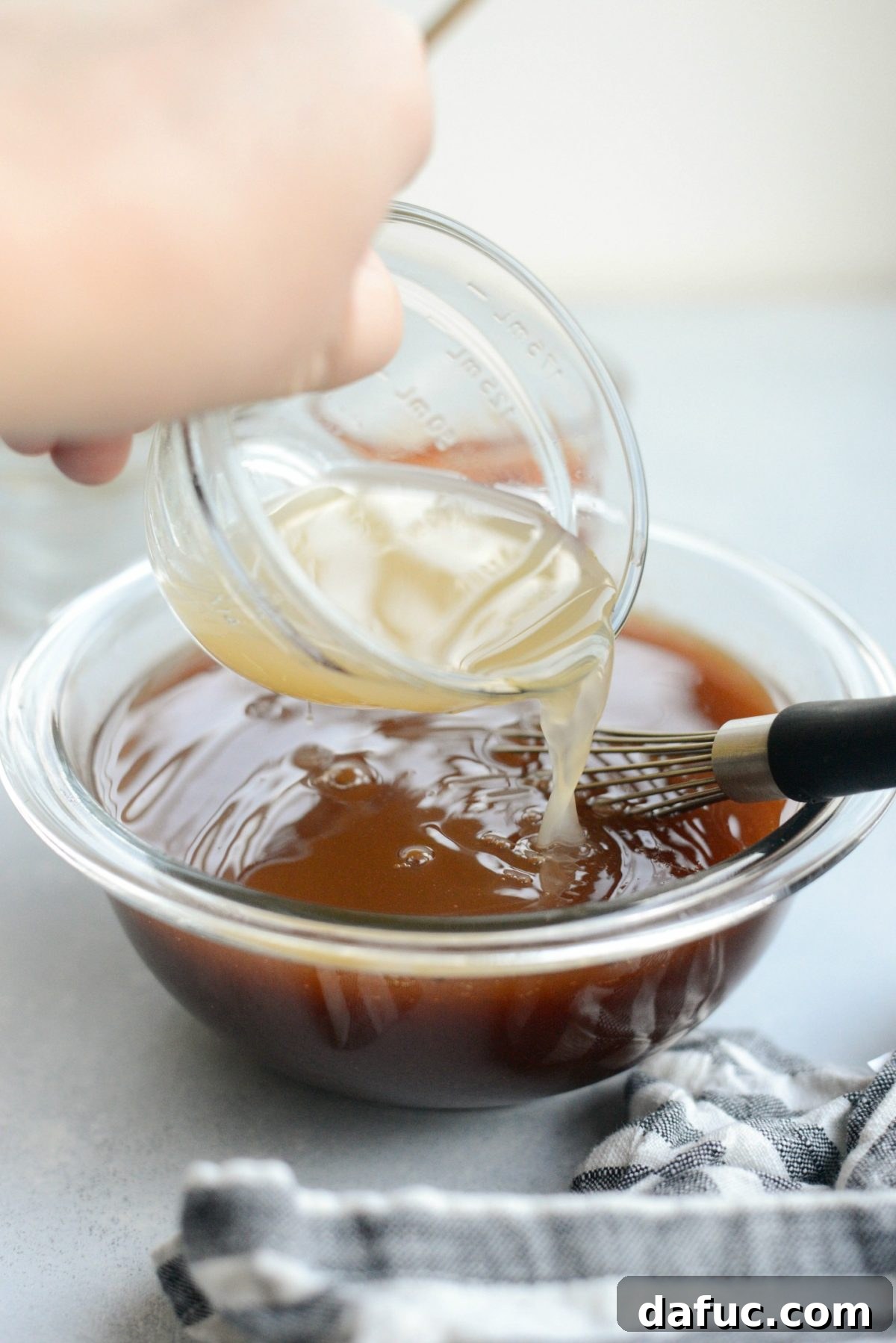 pouring low-sodium chicken broth into sweet and sour sauce.