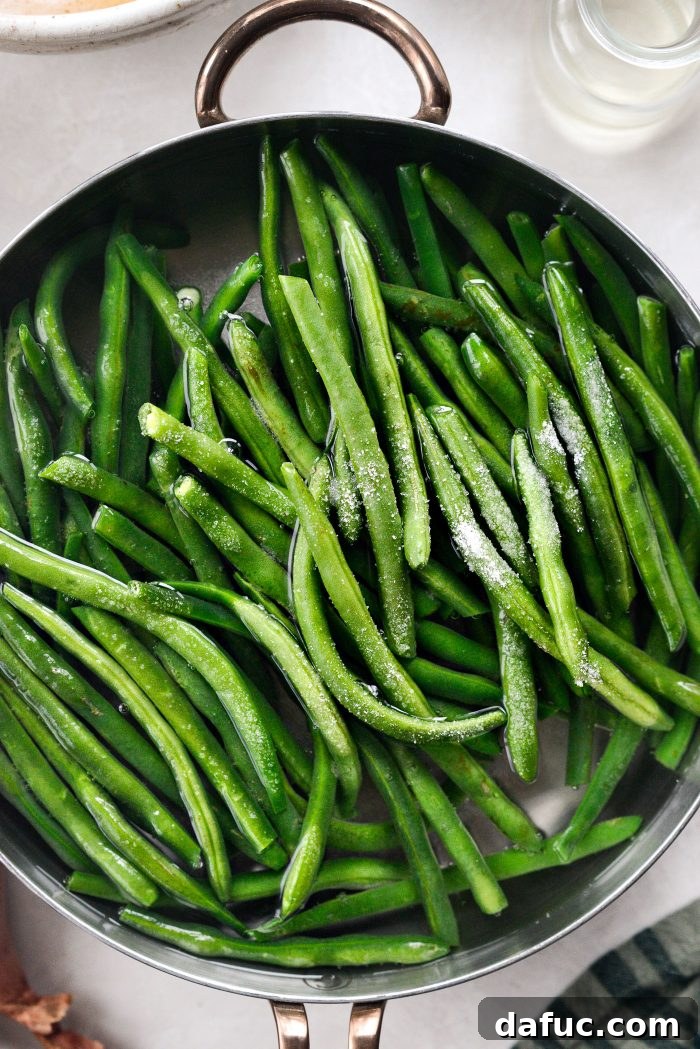 Crispy Shallot Green Bean Casserole 8 Fresh green beans being added to boiling water with a sprinkle of sea salt.