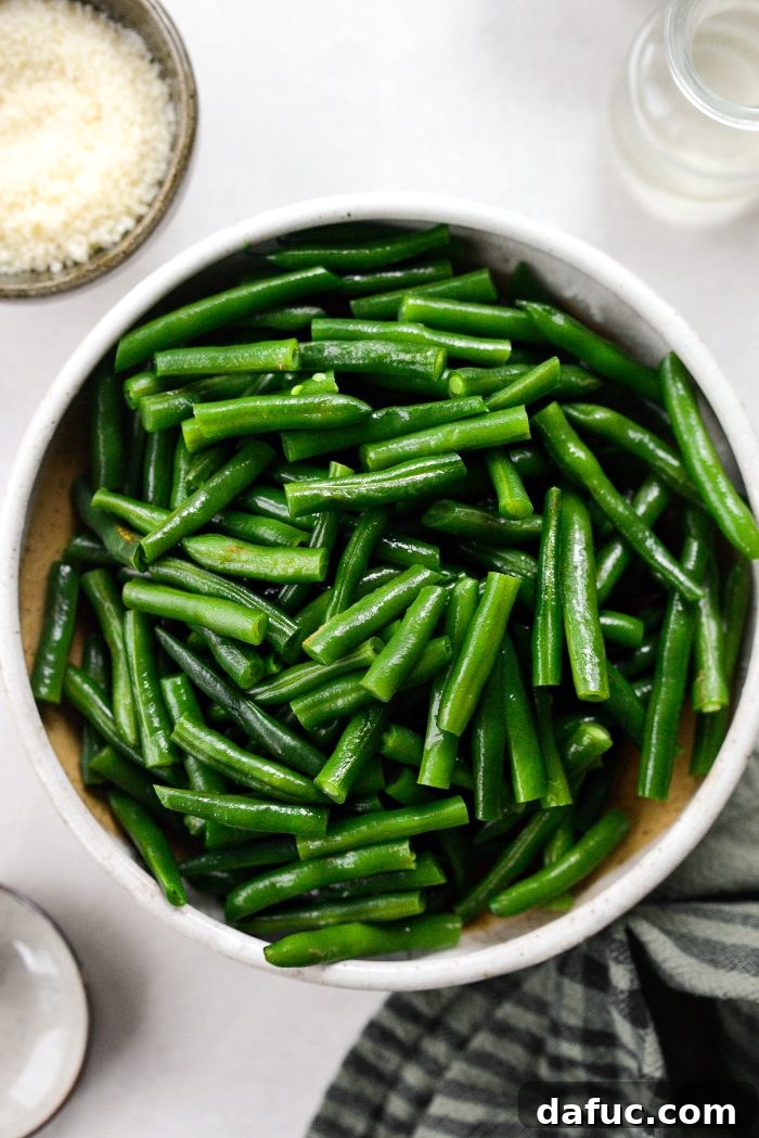 Crispy Shallot Green Bean Casserole 10 Drained and dried green beans being cut into smaller, bite-sized pieces on a cutting board.