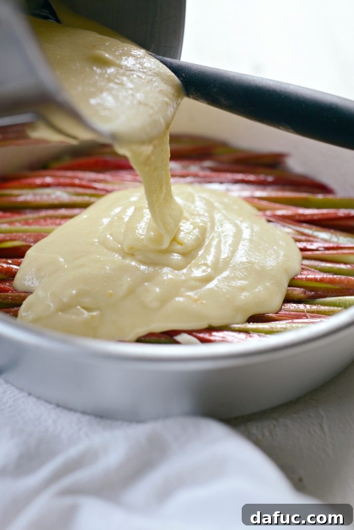 Martha Sweet Rhubarb Flip 22 Cake batter being poured evenly over the rhubarb layer in the cake pan