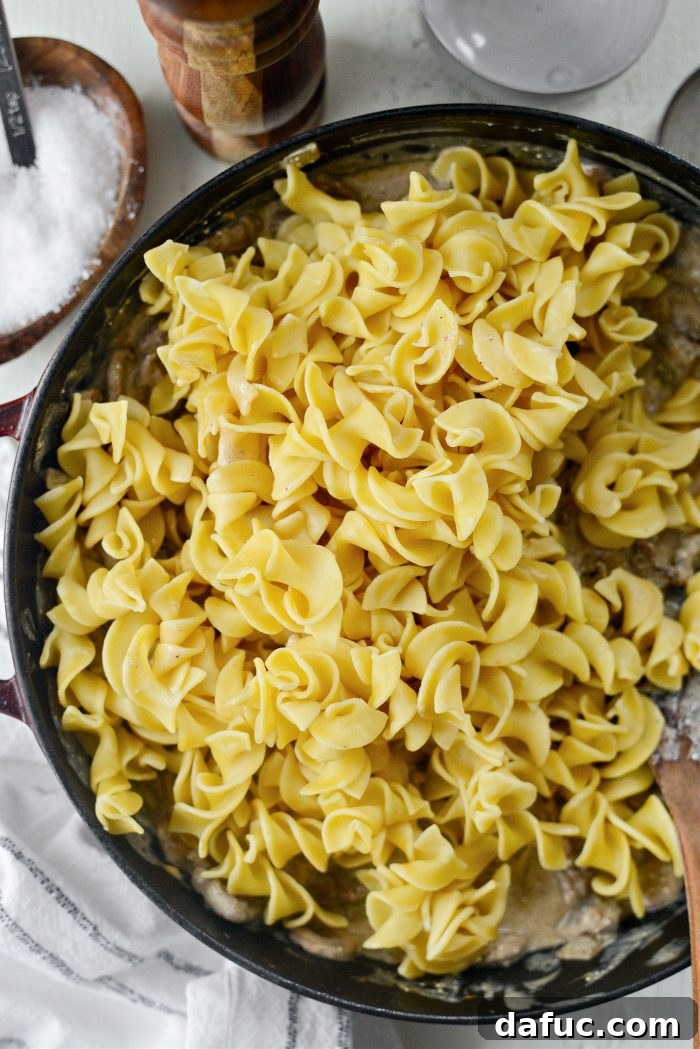 Hearty Homestyle Beef Stroganoff 25 Adding cooked egg noodles to the Beef Stroganoff and tossing to combine