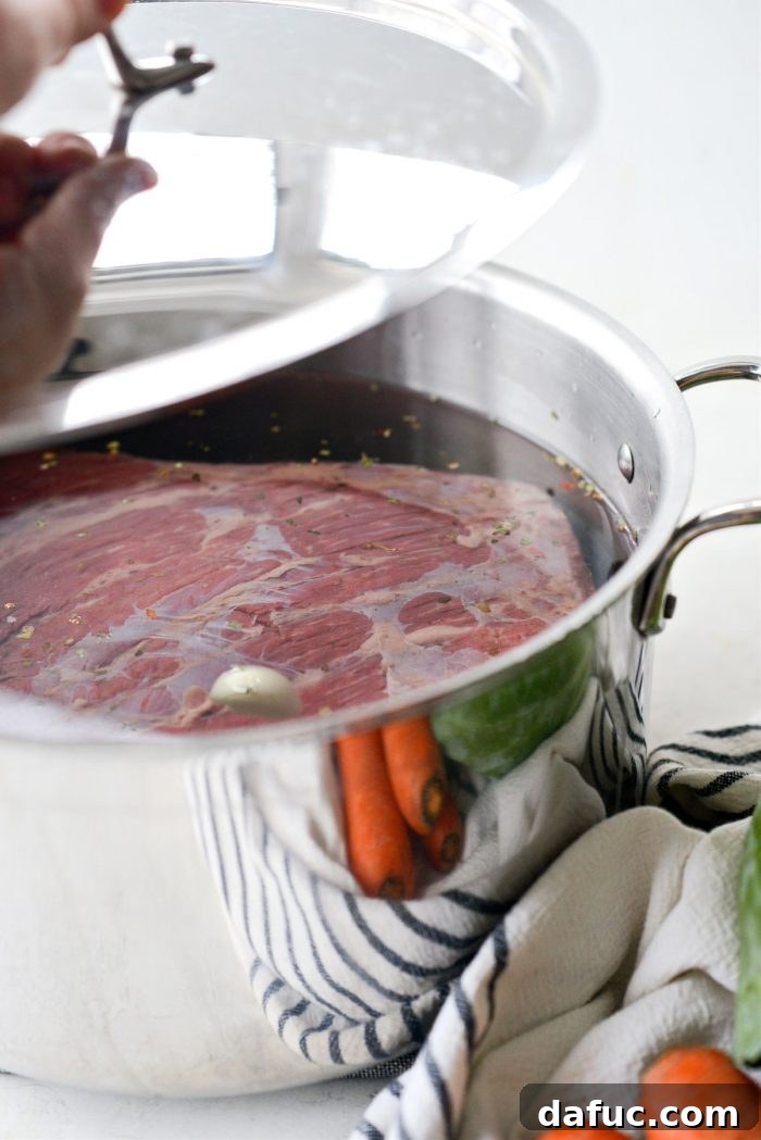 Succulent Corned Beef and Cabbage 8 A large stockpot with corned beef and water, covered with a lid, preparing for a low and slow simmer