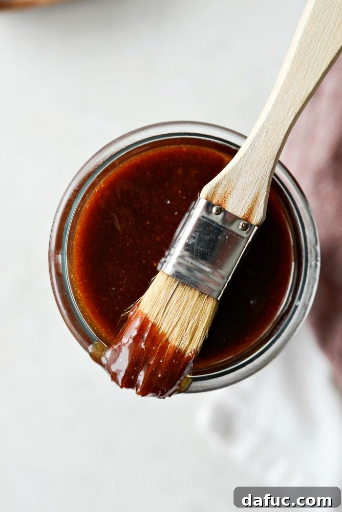 A final close-up of a rustic wooden spoon dipped into a bowl of homemade sweet barbecue sauce, showcasing its inviting texture and rich color.