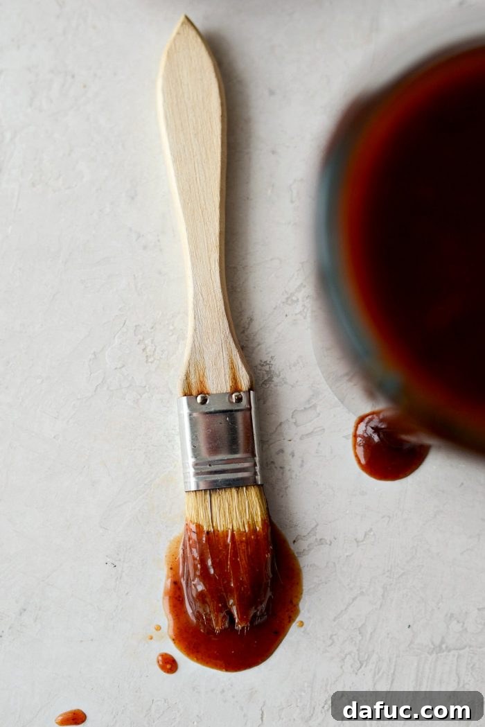 Closeup of homemade sweet barbecue sauce in a mixing bowl, showing its thick texture and vibrant color, ready to be stored.