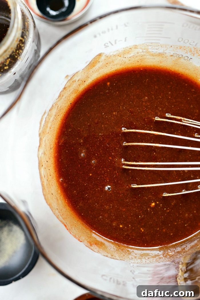 Whisking all ingredients together in a mixing bowl to make homemade sweet barbecue sauce, ensuring everything is well combined.