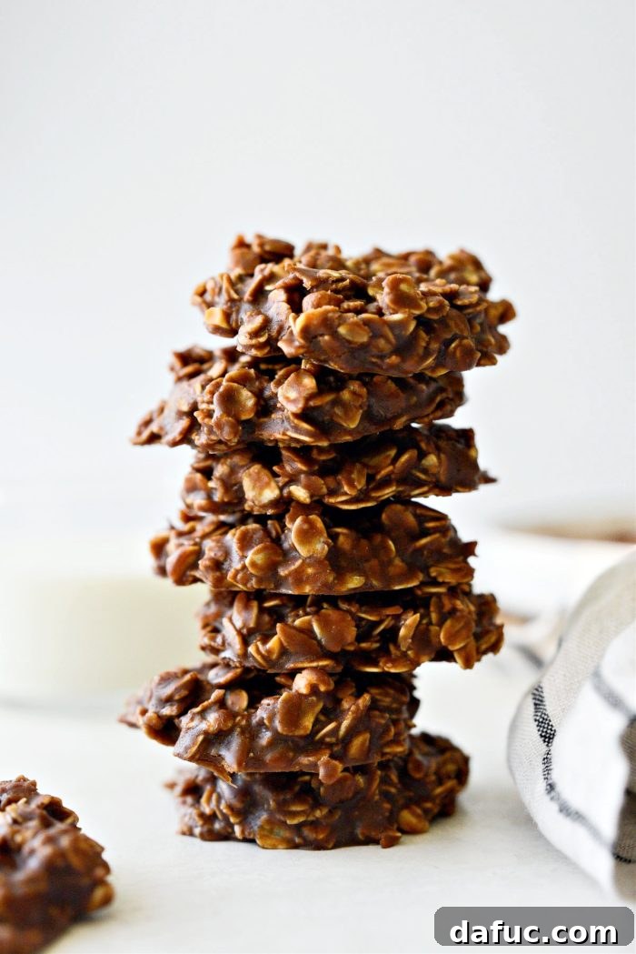 Fudgy No-Bake Oatmeal Delights 2 No-Bake Chocolate Oatmeal Cookies piled on a wooden surface