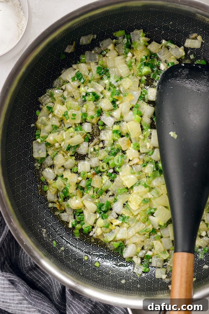 Stirring sautéed onions, green onions, and garlic in a skillet