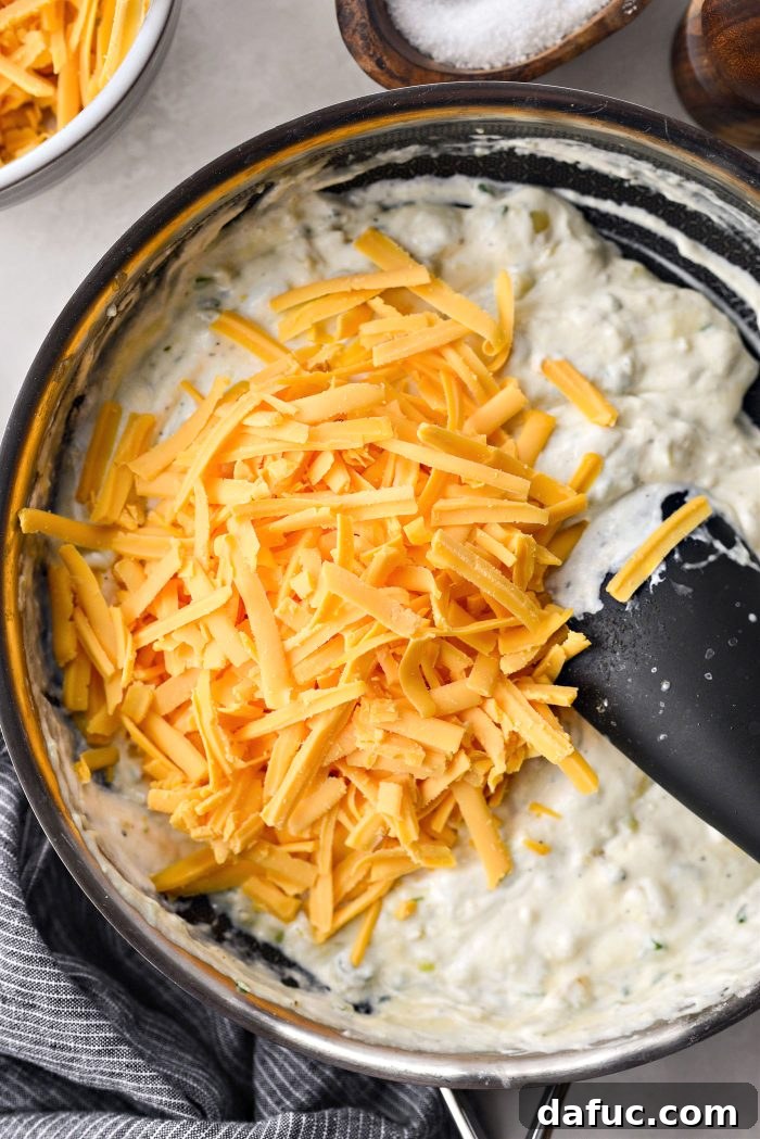 Stirring the sharp cheddar cheese into the creamy sauce until well combined