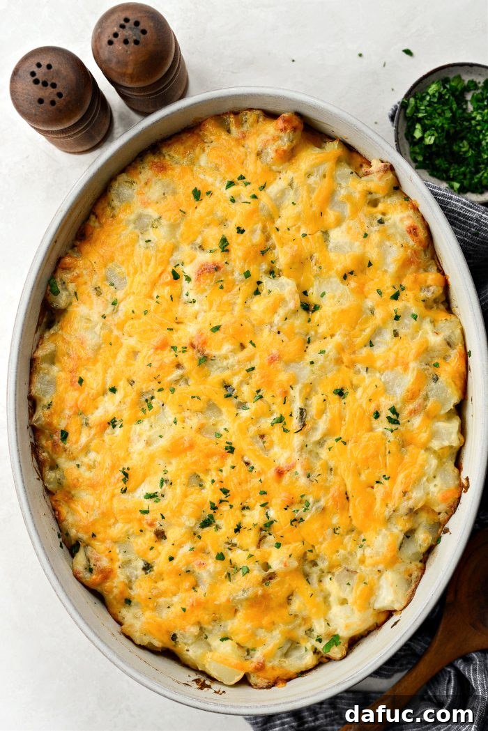 A large serving spoon scooping homemade cheesy potatoes from a dish