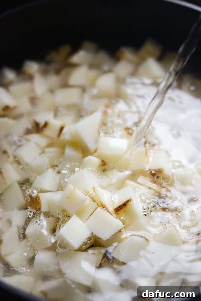 Diced potatoes added to a large pot, filled with water for boiling
