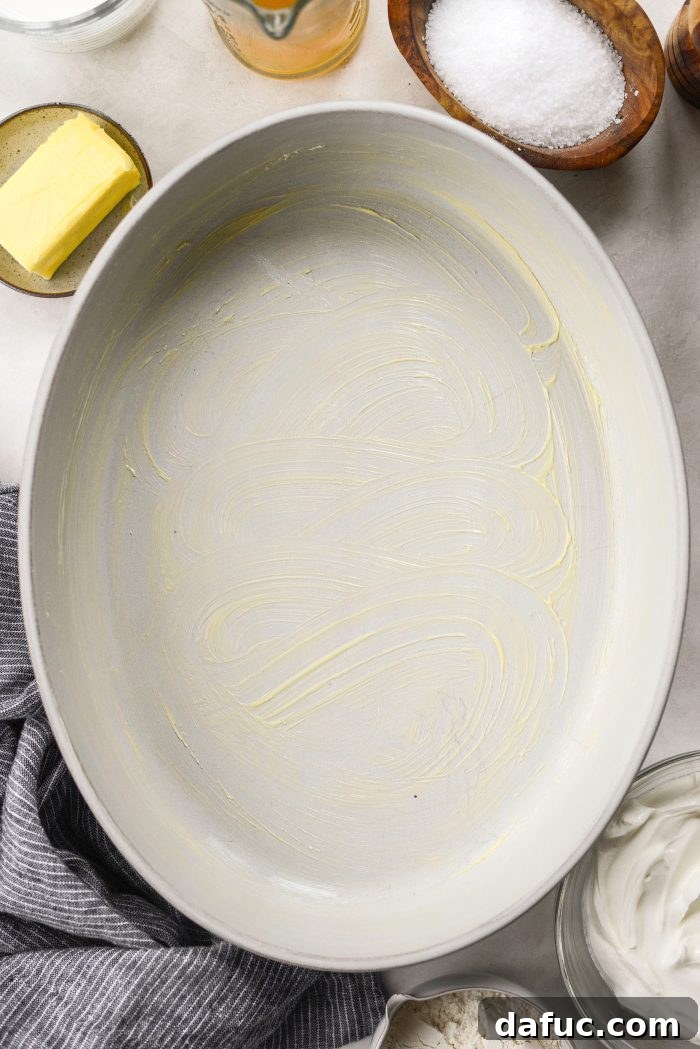 Greased baking dish and oven dial set to preheat