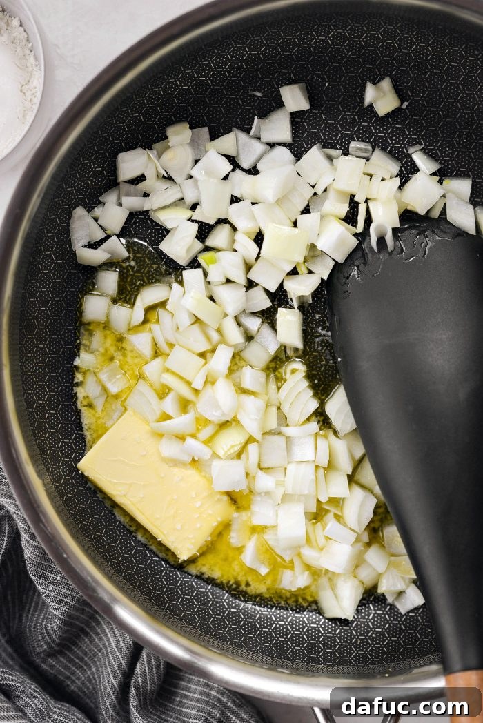 Butter melting in a skillet, with diced yellow onion and a pinch of salt added