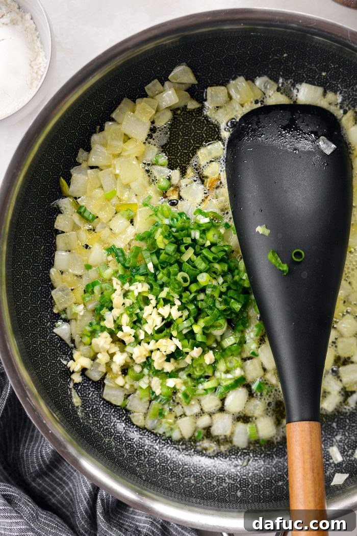 Softened yellow onion in a skillet, with sliced green onion and minced garlic added