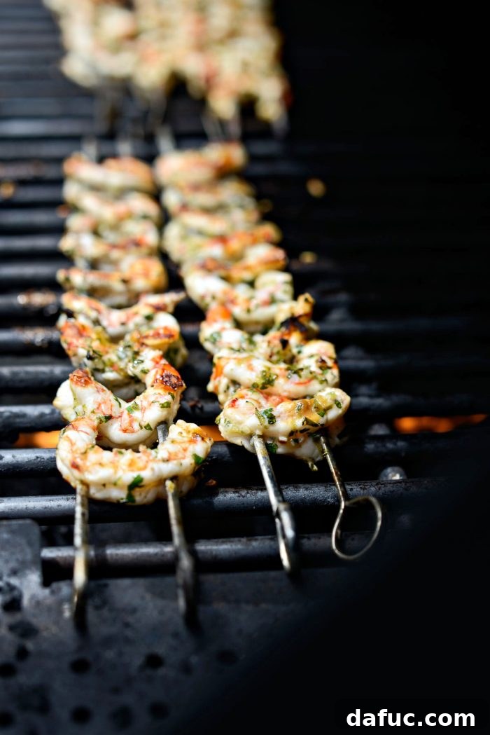 Grilled shrimp skewers, now opaque and pink, ready to be flipped