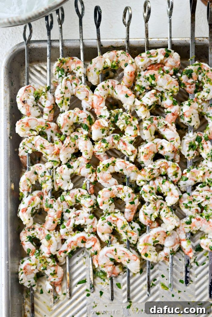 Raw shrimp being threaded onto double skewers