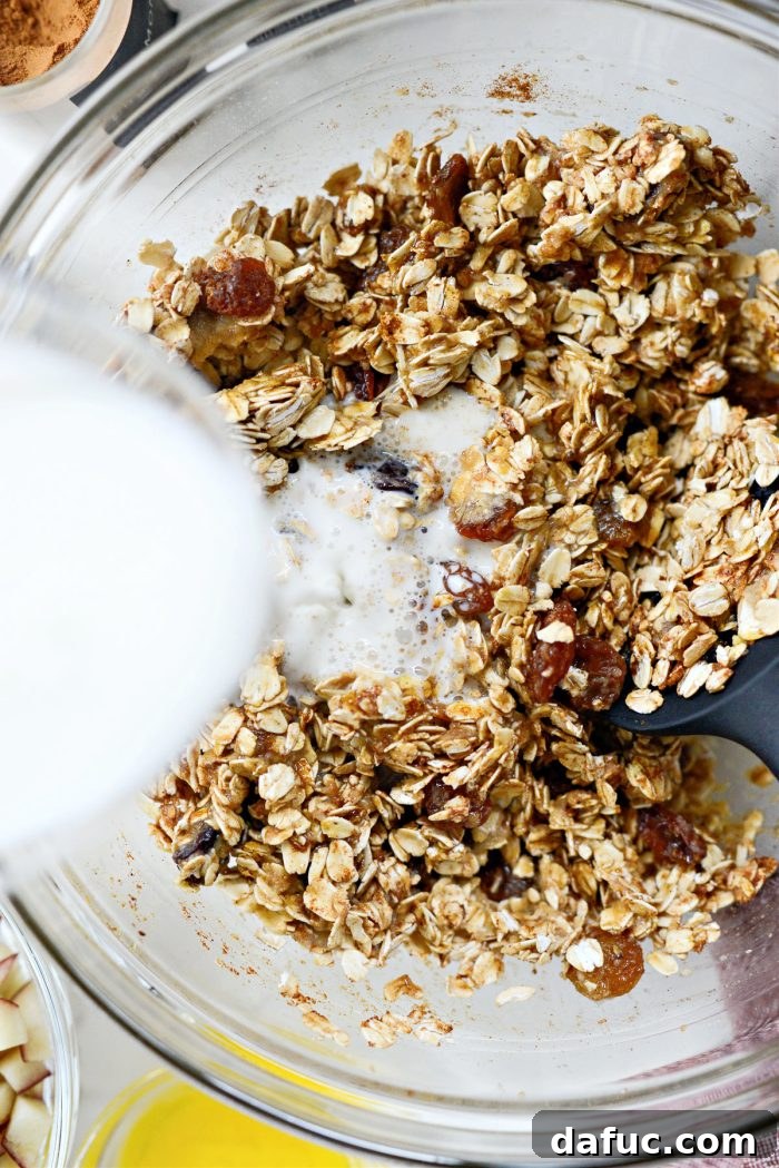 Warm Apple Cinnamon Oat Bake 6 Pouring milk into a bowl containing the mixed oatmeal base ingredients, demonstrating the next step in preparation