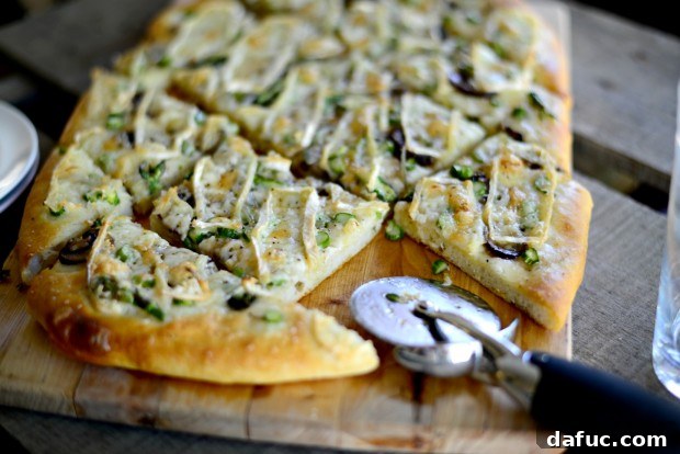 A slice of Asparagus, Mushroom, and Brie Flatbread, showing the melted cheese and vibrant vegetables, ready to be served.
