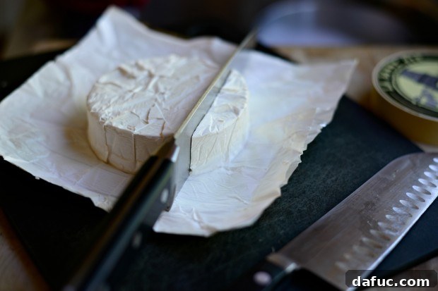 Soft-ripened brie cheese, sliced thinly and ready to be placed on the flatbread, promising a creamy, melted topping.