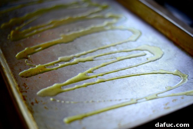 Olive oil drizzled generously onto a rimmed sheet pan, creating a non-stick surface and enhancing flavor for the flatbread.