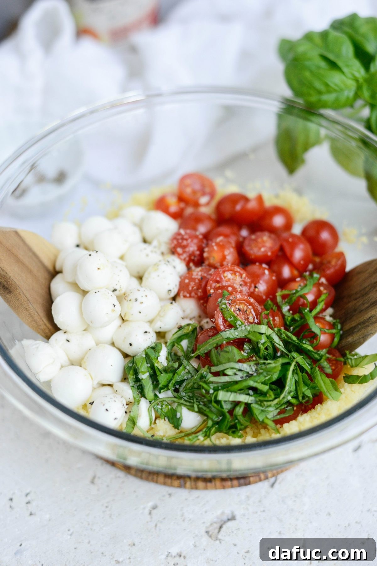 Vibrant Caprese Couscous 8 Adding mozzarella, tomatoes, basil, salt, and pepper to couscous