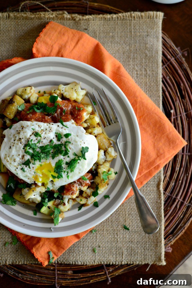Close-up of a rustic breakfast skillet filled with colorful summer vegetables and a perfectly cooked fried egg, ready to be enjoyed.