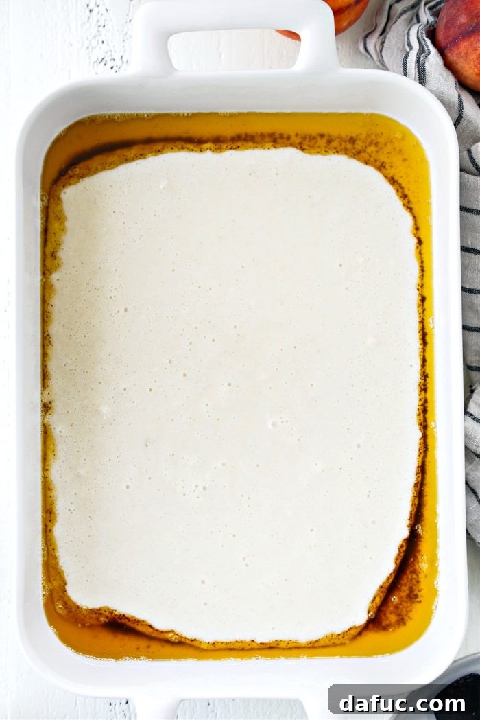 A 9x13 baking dish with browned butter at the bottom and the white cobbler batter layered on top