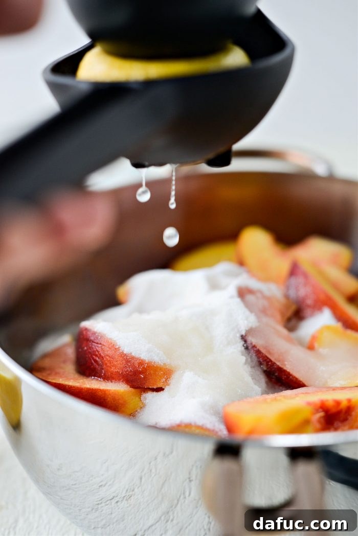 Squeezing fresh lemon juice over the peaches and sugar in a saucepan