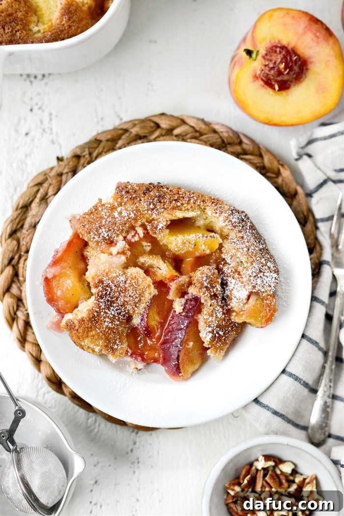 A close-up of the finished Brown Butter Peach Cobbler, showing a serving scoop in a shallow bowl
