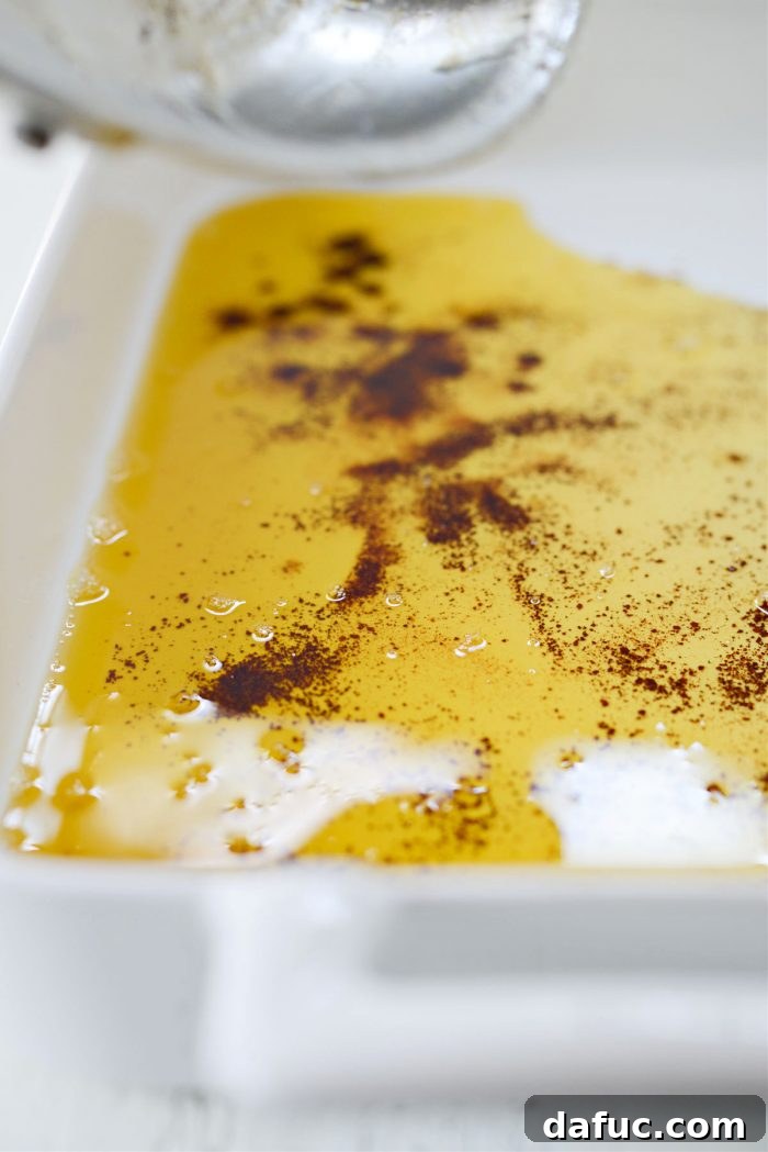 Pouring golden brown butter from a skillet into a glass 9x13 baking dish