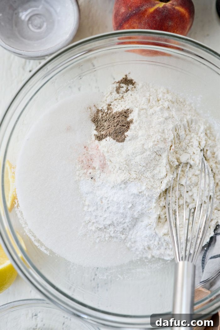 Dry ingredients for the cobbler batter, including flour, sugar, and baking powder, in a mixing bowl