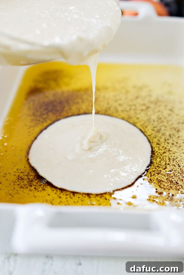Pouring the smooth cobbler batter over the browned butter in a 9x13 baking dish