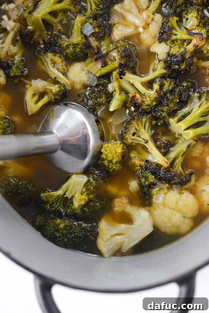 Using an immersion blender to puree roasted broccoli cauliflower soup