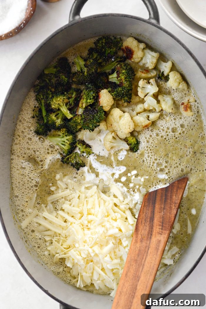 Adding heavy cream, reserved roasted vegetables, and white cheddar cheese to soup