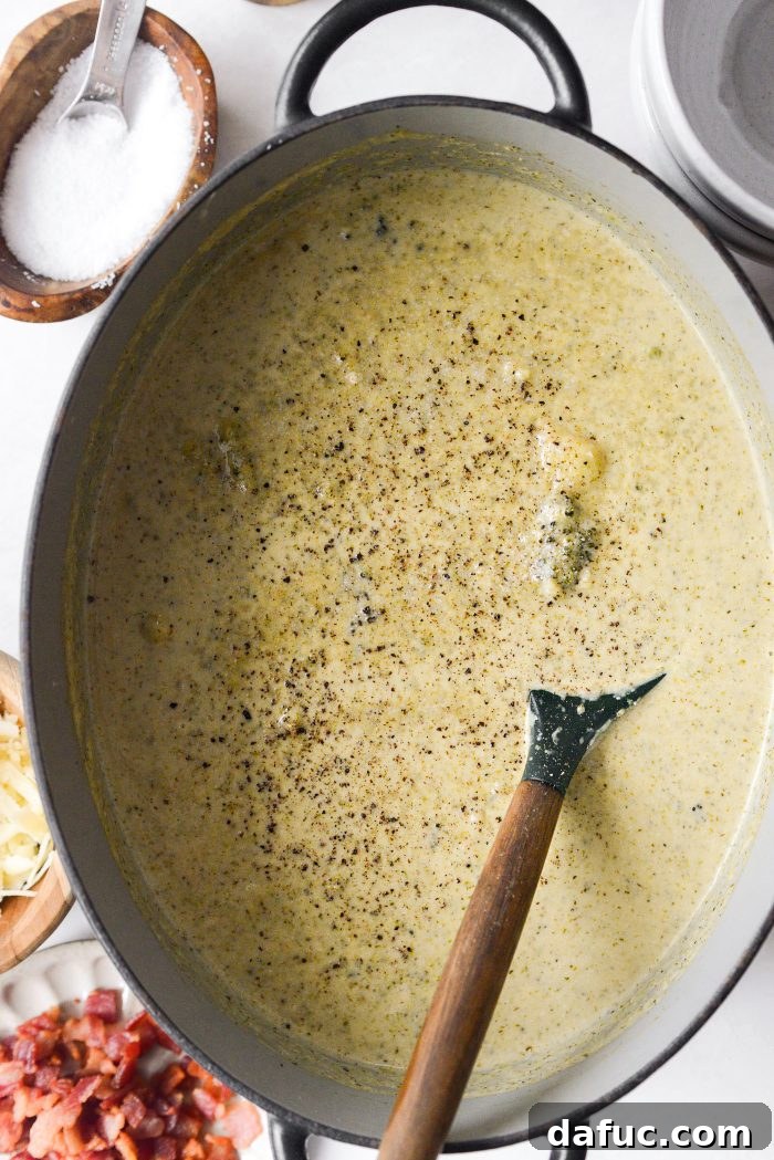 Seasoning creamy broccoli cauliflower soup with salt and pepper